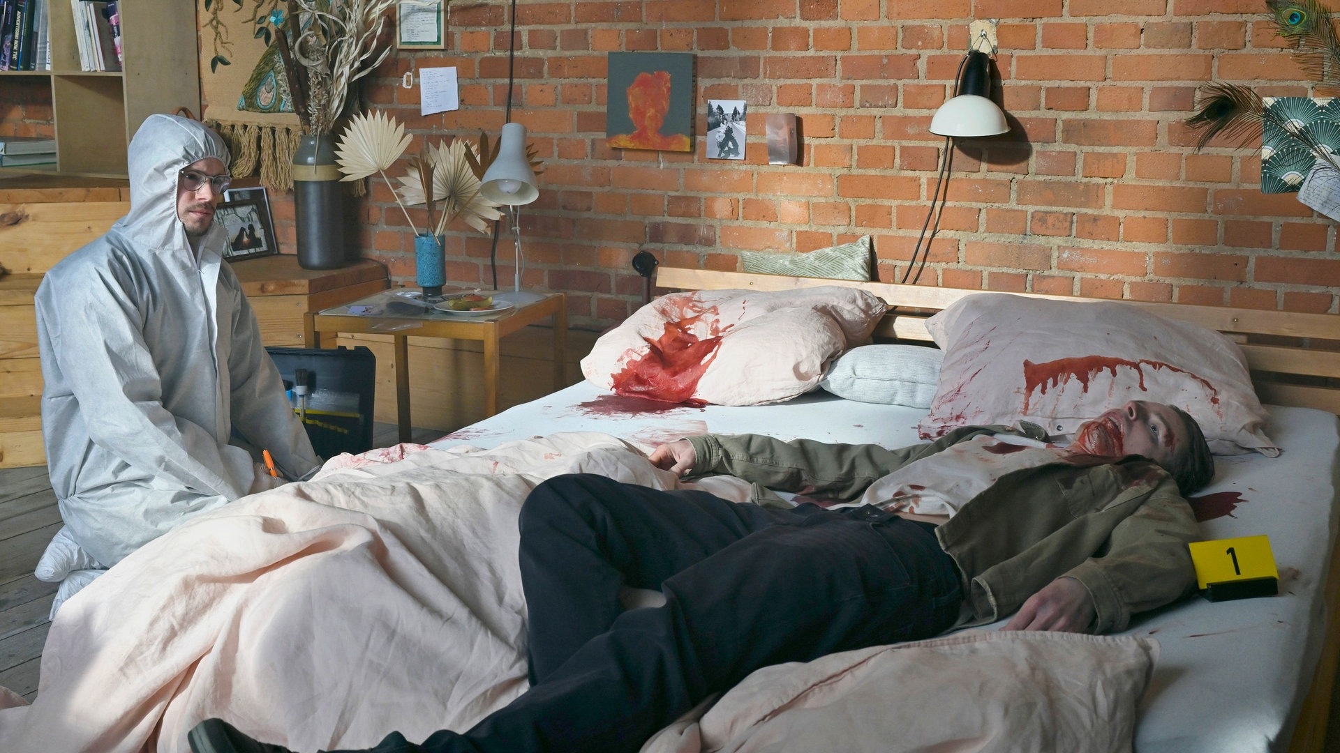 Foto: ard-foto s2-intern/extern, MDR / MadeFor / Hardy Spitz Tatort-Kritik Dresden „Was ihr nicht seht“: Ein Gerichtsmediziener kniet neben einer Leiche die auf einem Bett liegt (Foto: ard-foto s2-intern/extern, MDR / MadeFor / Hardy Spitz)