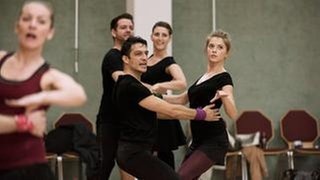 Proben bis zur Erschöpfung: Marie Ade (Mersiha Husagic, vorne rechts) und Remo Dorn (Max Hemmersdorfer, vorne links) bereiten sich mit der Tanzsportgemeinschaft auf einen wichtigen Wettkampf vor. (Foto: WDR/Martin Menke) Proben bis zur Erschöpfung: Marie Ade (Mersiha Husagic, vorne rechts) und Remo Dorn (Max Hemmersdorfer, vorne links) bereiten sich mit der Tanzsportgemeinschaft auf einen wichtigen Wettkampf vor.
