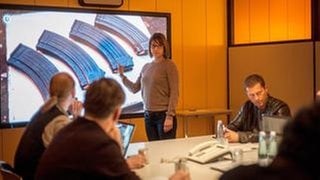 Sie berichtet im LKA-Besprechungsraum über die verwendeten Schnellfeuerwaffen.