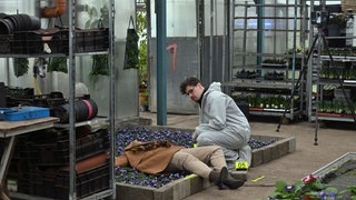 Gerichtsmediziner kniet neben Leiche.