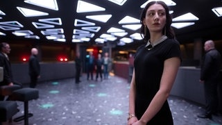 Tatort-Kritik Wien „Azra“: Tinatin Datviani schaut ausdruckslos von Männern in Anzügen weg (Foto: ard-foto s2-intern/extern, ARD Degeto/ORF/Felix Vratny) Tatort-Kritik Wien „Azra“: Tinatin Datviani schaut ausdruckslos von Männern in Anzügen weg