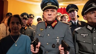 Tatort-Kritik Wiesbaden „Murot und das Paradies“: Murot in Nazi Uniform und zwei gezogenen Waffen (Foto: ard-foto s2-intern/extern, HR / Bettina Müller) Tatort-Kritik Wiesbaden „Murot und das Paradies“: Murot in Nazi Uniform und zwei gezogenen Waffen