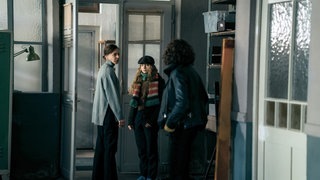 Tatort Ludwigshafen „Avatar“: Drei junge Frauen stehen in einem düsteren Raum. Lena Odenthal (Ulrike Folkerts) fragt sich, welche Beziehung zwischen ihrer mutmaßlichen Mordzeugin Julia Da Borg (Bernadette Heerwagen) und der Schülerin Marie (Leni Deschner) bestehen.