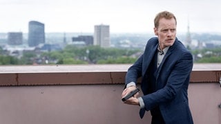 Szenenbild von Tatort „Abstellgleis“ aus Dortmund: Daniel Kossik vom LKA mit Waffe auf einem Hochhaus (Foto: ard-foto s2-intern/extern, WDR/Thomas Kost) Szenenbild von Tatort „Abstellgleis“ aus Dortmund: Daniel Kossik vom LKA mit Waffe auf einem Hochhaus