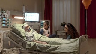 Eine Frau mit Kind sitzt am Krankenbett der Frau, die einen Unfall hatte. Szenenbild Polizeiruf 110 „Widerfahrnis“ aus Magdeburg (Foto: © MDR/filmpool fiction/Stefan Erhard) Eine Frau mit Kind sitzt am Krankenbett der Frau, die einen Unfall hatte. Szenenbild Polizeiruf 110 „Widerfahrnis“ aus Magdeburg