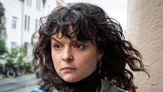 Szenenbild Tatort „Solange du atmest“ aus Bremen: Eine Frau mit dunklen Locken schaut kritisch. (Foto: ard-foto s2-intern/extern, Radio Bremen / Claudia Konerding) Szenenbild Tatort „Solange du atmest“ aus Bremen: Eine Frau mit dunklen Locken schaut kritisch.