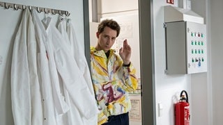 Szenenbild Tatort „Solange du atmest“ aus Bremen: Ein Mann in bunter Jacke schaut durch die Tür in ein Zimmer hinein. (Foto: ard-foto s2-intern/extern, Radio Bremen / Claudia Konerding) Szenenbild Tatort „Solange du atmest“ aus Bremen: Ein Mann in bunter Jacke schaut durch die Tür in ein Zimmer hinein.