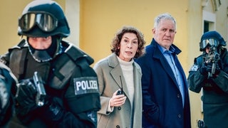 Szenenbild aus dem Tatort „Wir sind nicht zu fassen!“ aus Wien: Die Ermittler Moritz Eisner und Bibi Fellner zwischen zwei bewaffneten Polizisten (Foto: ard-foto s3, ORF/Petro Domenigg) Szenenbild aus dem Tatort „Wir sind nicht zu fassen!“ aus Wien: Die Ermittler Moritz Eisner und Bibi Fellner zwischen zwei bewaffneten Polizisten