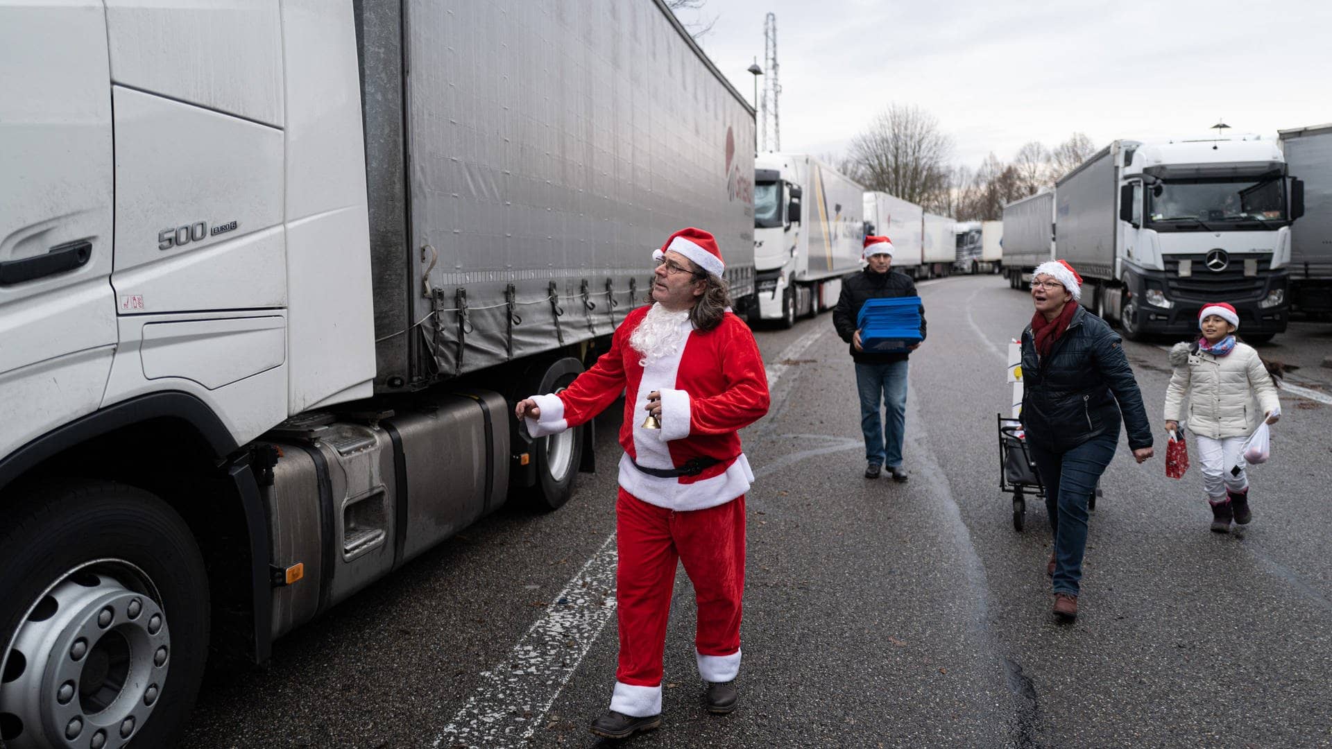 Juan Pedro Garcia Rosales in Weihnachtsmannkostüm und seine Helfer laufen mit Geschenken zu einem Lkw.