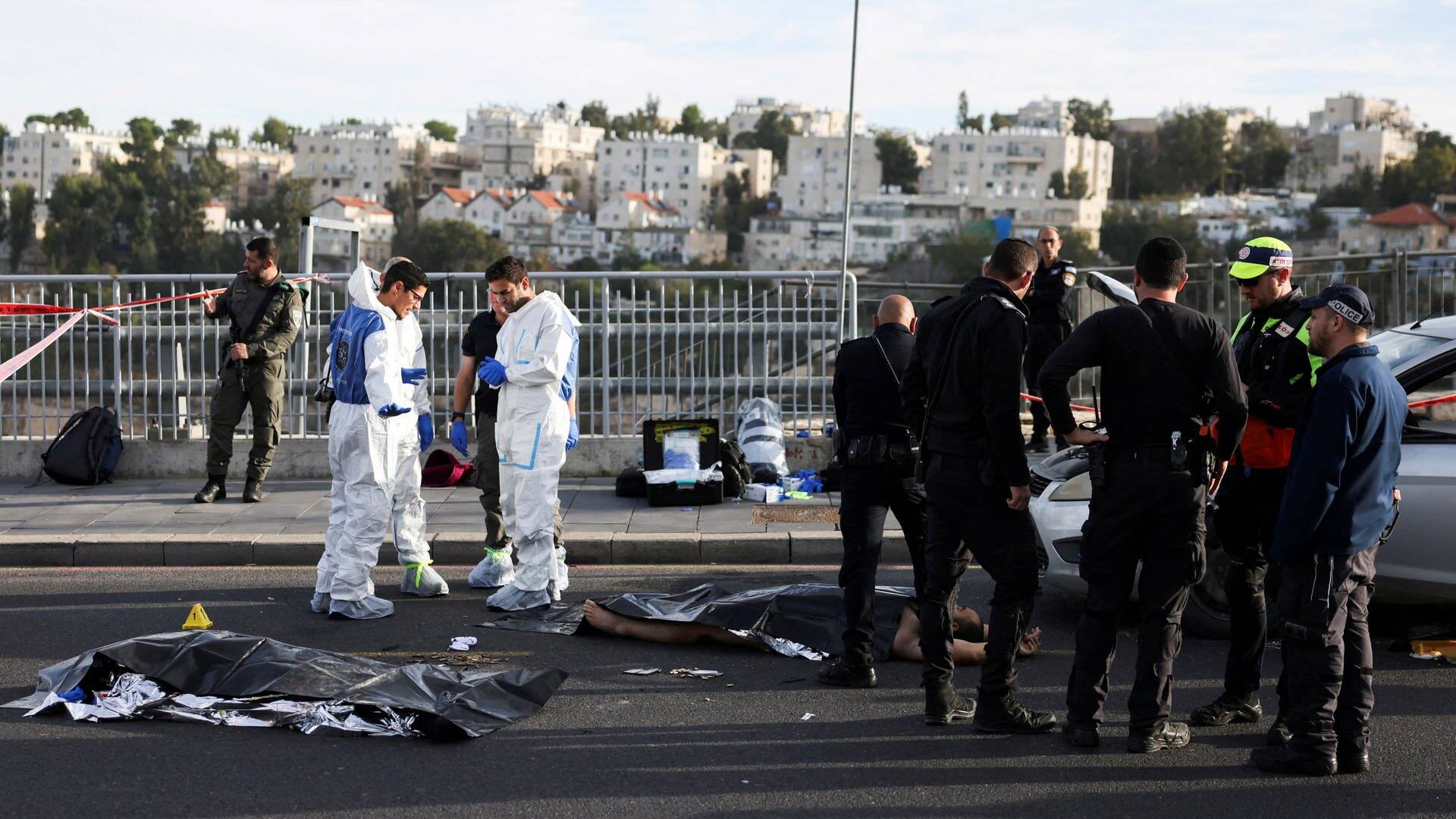 Leichensäcke liegen am Ort eines Anschlags in Jerusalem, Polizisten und Spurensicherer stehen dabei (Foto: Reuters, REUTERS/Ronen Zvulun)