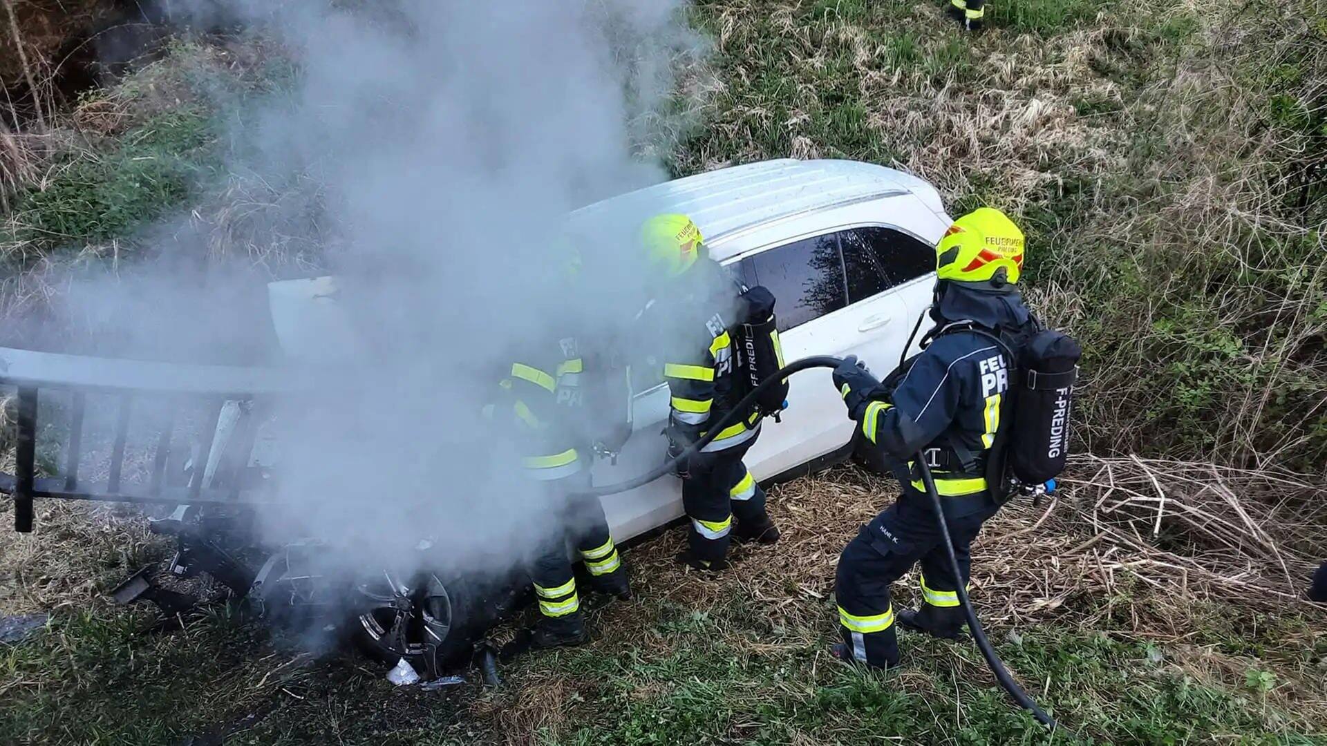 Feuerwehrleute löschen ein Auto nach einem Unfall in Österreich.