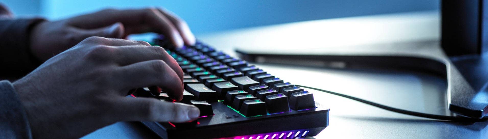 Hände liegen auf einer Gaming-Tastatur, daneben eine Gaming-Maus