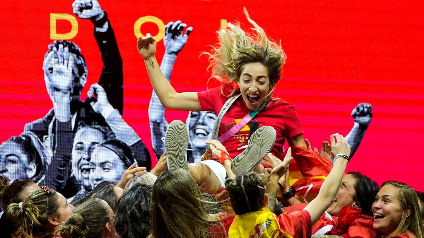 Spielerinnen der spanischen Frauenfußballnationalmannschaft heben die spanische Nationalspielerin Olga Carmona hoch, während sie auf der Bühne ihren Sieg bei der Fußballweltmeisterschaft feiern.