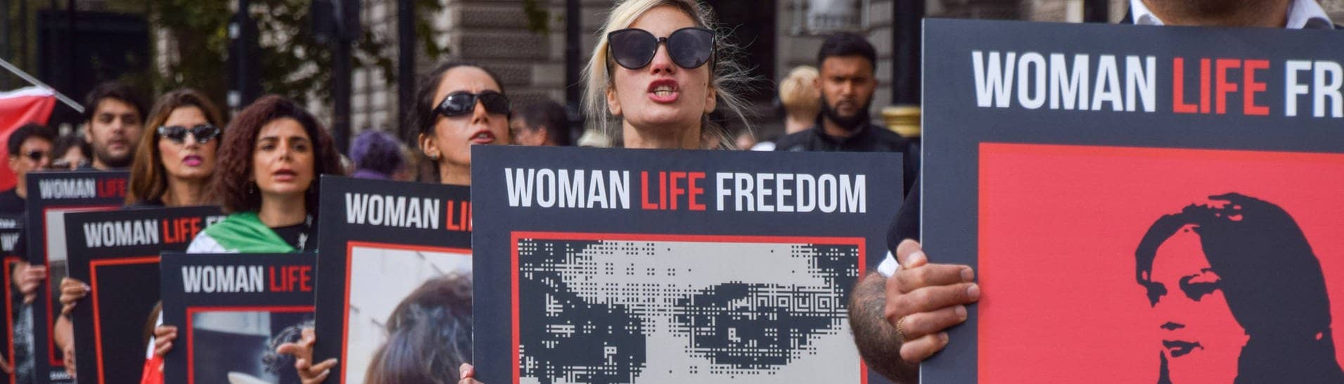 Nach dem Tod von Mahsa Amini im Iran:  Demonstrierende tragen Plakate auf denen steht „Woman, Life, Freedom“