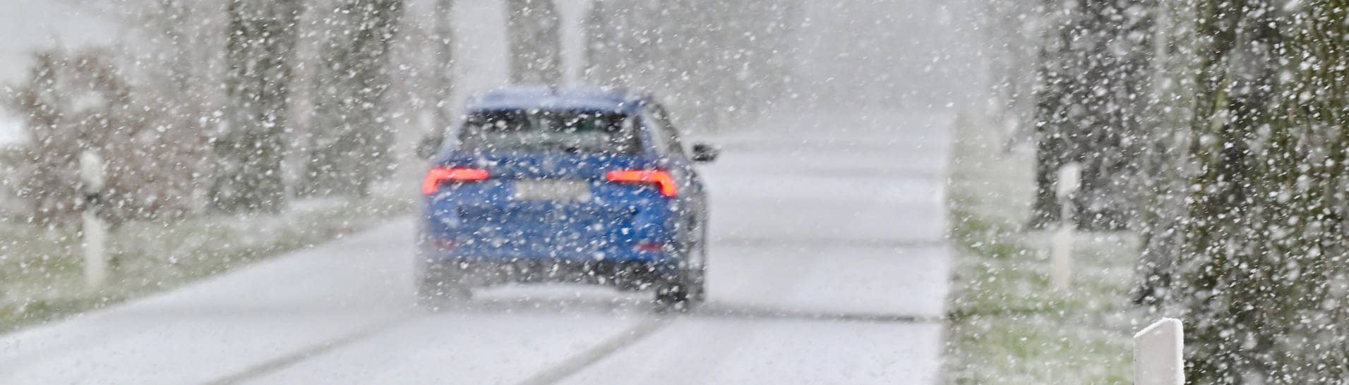 Ein Auto fährt durch Schneefall