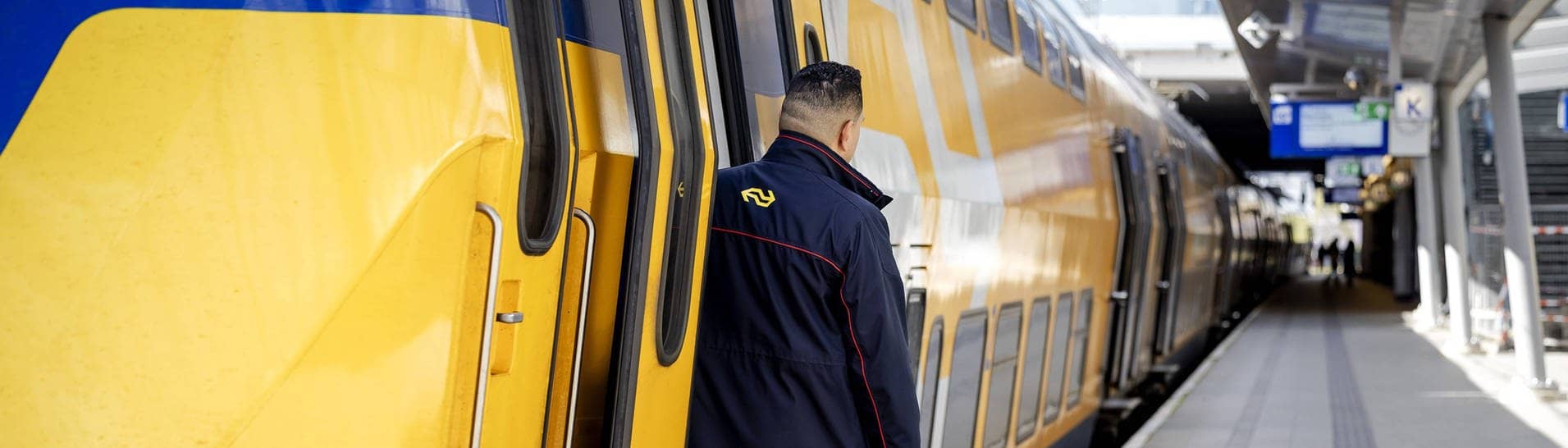 Ein Zugbegleiter schaut aus einem Zug am Bahnsteig am Bahnhof Utrecht (Niederlande)