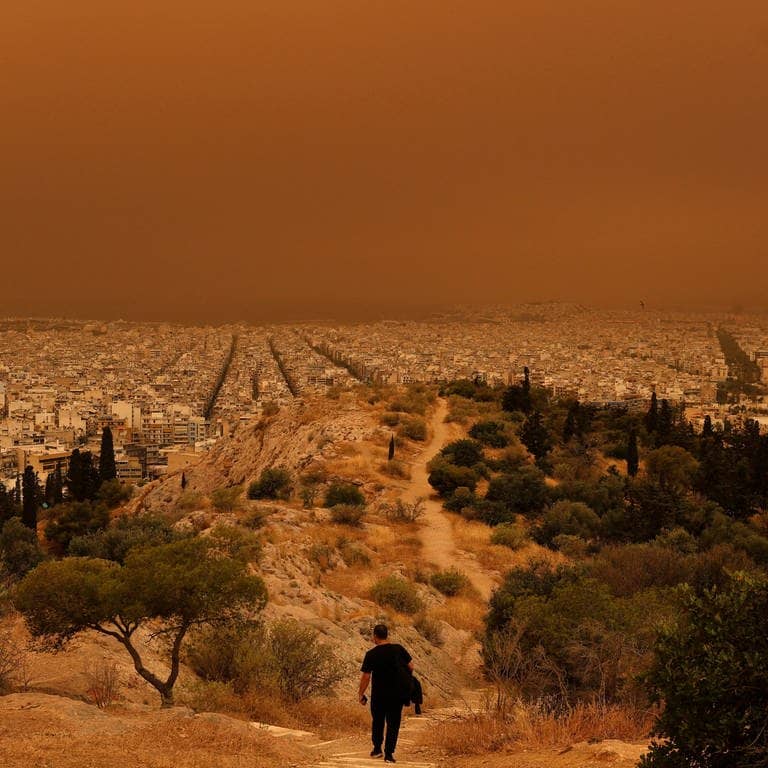 Roter Himmel, rote Erde: Ein Mann wandert am Dienstag in den Hügeln über Athen. (Foto: Reuters)