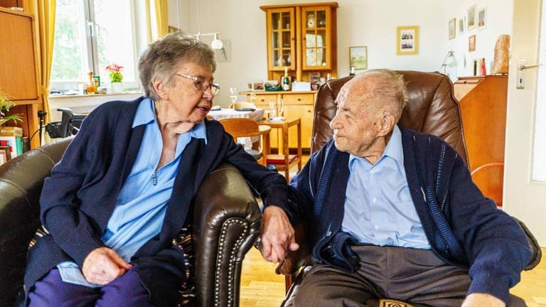 Ursula und Gottfried Schmelzer sitzen in ihrem Wohnzimmer zusammen. Die beiden sind seit 80 Jahren verheiratet.