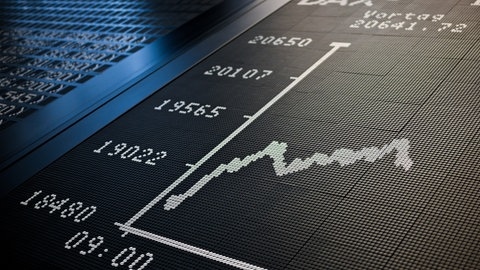 Ein Börsenhändler sitzt an der Frankfurter Börse und die Kurve des Dax zeigt unter 20.000 Punkte an.