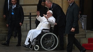 Papst Franziskus wird im Rollstuhl geschoben und streckt die Arme in die Höhe. (Foto: dpa Bildfunk, picture alliance/dpa | Harald Tittel) Papst Franziskus wird im Rollstuhl geschoben und streckt die Arme in die Höhe.