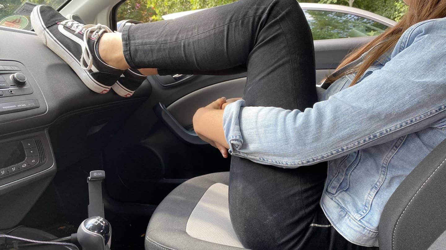 Frau stellt Beine auf Armaturenbrett im Auto