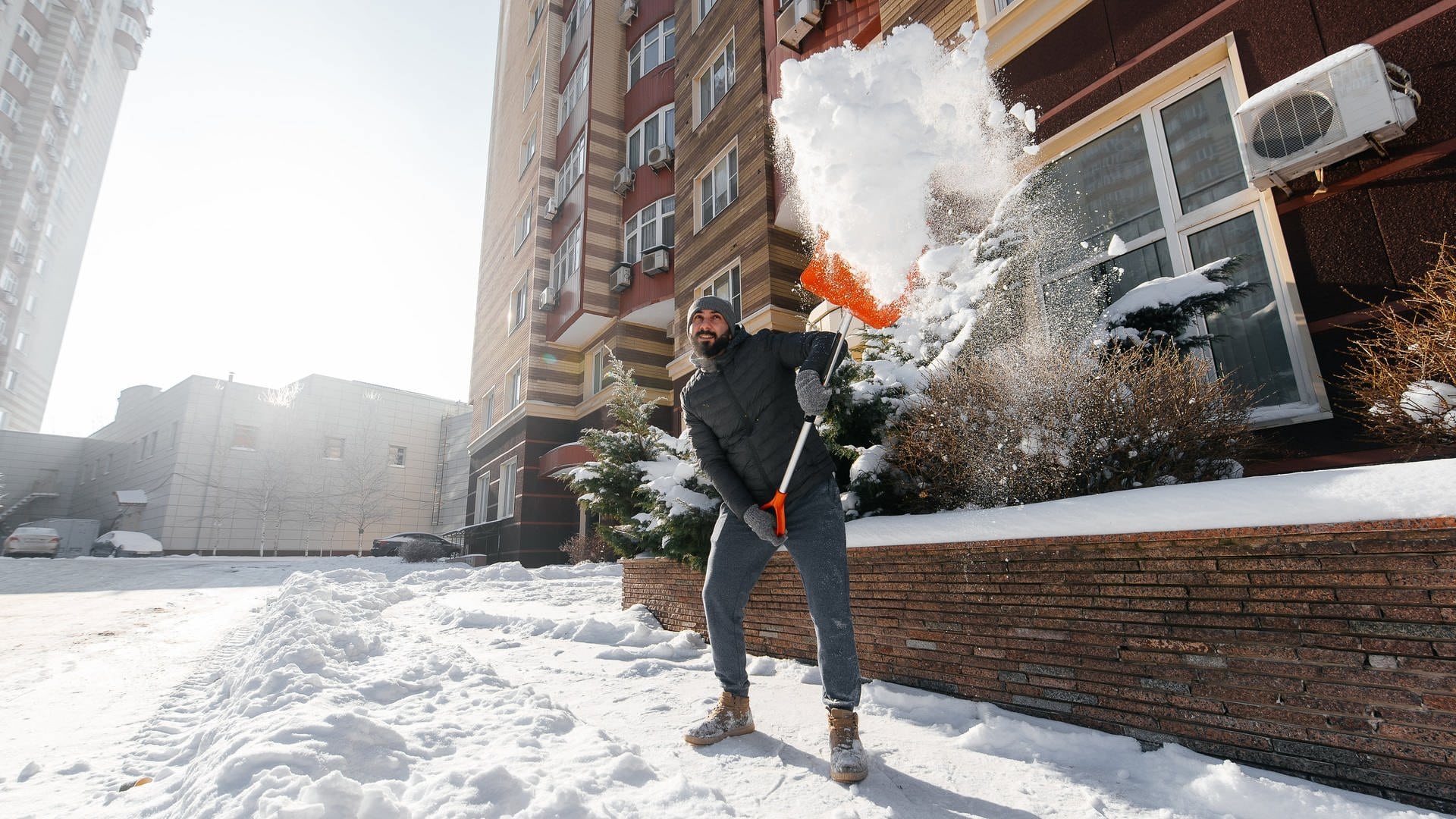 Mann räumt Schnee mit einer Schneeschaufel weg