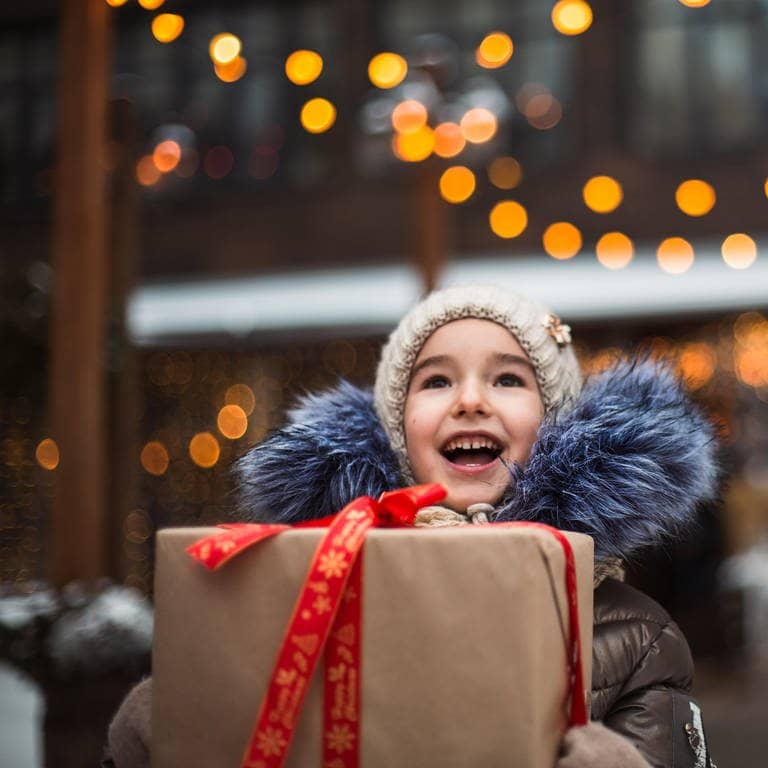 Tolle Geschenkideen: Ein Kind freut sich über ein Geschenk an Weihnachten.