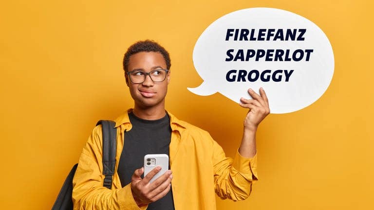 Ein junger Mann hält ein Handy in der einen Hand und in der anderen Hand eine Sprechblase mit den Wörtern Firlefanz, Sapperlot und groggy.