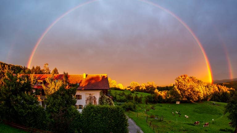 Nach ergiebigem Regen zeigt sich in der Abendsonne ein Regenbogen über dem Staffelsee bei Murnau