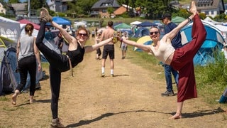 Zwei junge Frau beim Bier-Yoga auf dem Campingplatz von Rock am Ring 2023 (Foto: SWR3, SWR3 / Ronny Krautz) Zwei junge Frau beim Bier-Yoga auf dem Campingplatz von Rock am Ring 2023