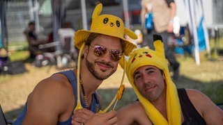 Zwei Männer mit gelben Pikachu-Hüten sind vor Zelten bei Rock am Ring (Foto: SWR3, SWR3 / Ronny Krautz) Zwei Männer mit gelben Pikachu-Hüten sind vor Zelten bei Rock am Ring