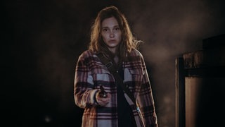 Szenenbild aus dem Polizeiruf 110 mit einer jungen Frau im Vordergrund (Foto: BR/Amalia Film und Dragonbird Films/Sabine Finger) Szenenbild aus dem Polizeiruf 110 mit einer jungen Frau im Vordergrund