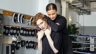 Szenenbild Tatort „Solange du atmest“ aus Bremen: Liv Moormann nimmt den Kopf ihrer Kollegin Linda Selb von hinten in einen Würgegriff, die versucht ihren Arm vom ihrem Hals wegzuziehen. (Foto: ard-foto s2-intern/extern, Radio Bremen / Claudia Konerding) Szenenbild Tatort „Solange du atmest“ aus Bremen: Liv Moormann nimmt den Kopf ihrer Kollegin Linda Selb von hinten in einen Würgegriff, die versucht ihren Arm vom ihrem Hals wegzuziehen.